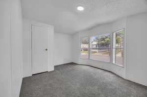 Unfurnished bedroom featuring a textured ceiling and carpet