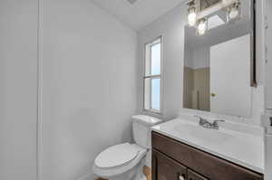 Bathroom with a wealth of natural light, a textured ceiling, vanity, and toilet