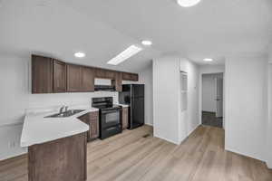 Kitchen featuring sink, light wood-type flooring, and black appliances