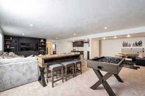 Recreation room with a textured ceiling and light colored carpet