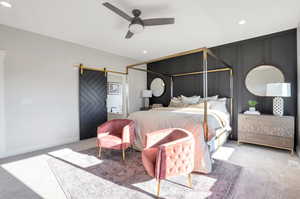 Bedroom featuring a barn door, ceiling fan, and light colored carpet