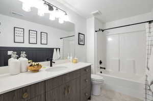 Full bathroom with toilet, shower / tub combo with curtain, a textured ceiling, and vanity