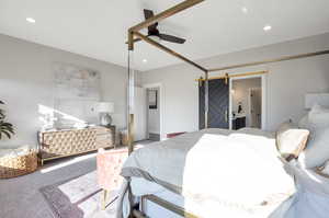 Carpeted bedroom with ceiling fan and a barn door