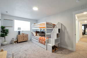 Carpeted bedroom with wood walls and a textured ceiling