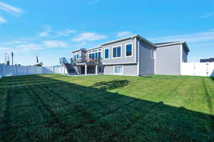 Rear view of property featuring a wooden deck and a lawn