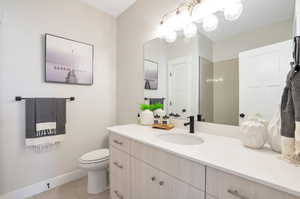 Bathroom with tiled shower, vanity, toilet, and tile patterned flooring