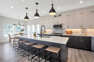 Kitchen featuring appliances with stainless steel finishes, pendant lighting, an island with sink, and a breakfast bar area