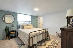 Carpeted bedroom with wood walls and a textured ceiling