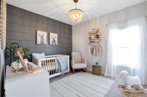 Bedroom featuring multiple windows, light colored carpet, a nursery area, and an inviting chandelier