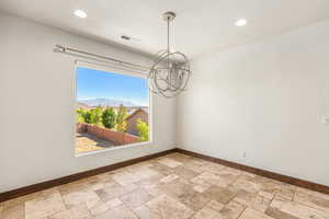 Unfurnished room featuring tile patterned flooring and a chandelier