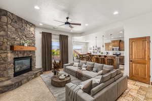 Tiled living room with ceiling fan and a fireplace