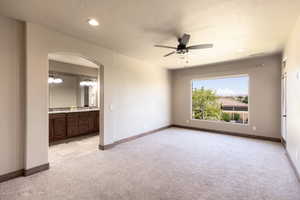 Unfurnished room with light colored carpet and ceiling fan with notable chandelier