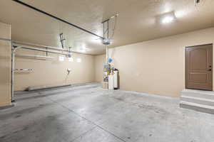 Garage featuring strapped water heater and a garage door opener