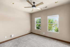 Carpeted spare room with ceiling fan and a healthy amount of sunlight