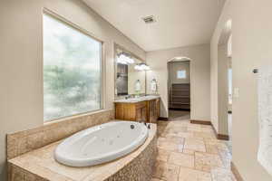 Bathroom with tiled bath, tile patterned flooring, a textured ceiling, and vanity