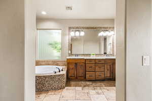 Bathroom with tiled bath, vanity, and tile patterned floors