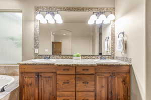 Bathroom featuring tiled tub and vanity