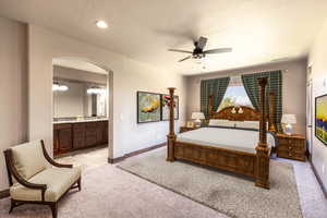 Bedroom with ceiling fan, light carpet, and connected bathroom