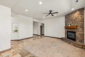 Unfurnished living room with ceiling fan, light carpet, and a fireplace