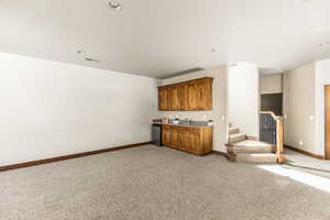 Unfurnished living room featuring sink and light carpet