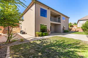 Back of property featuring a yard, a balcony, and central AC