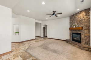 Unfurnished living room featuring ceiling fan, light tile patterned floors, and a fireplace