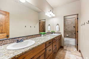 Full bathroom with tile patterned floors, tiled shower / bath combo, tasteful backsplash, vanity, and toilet