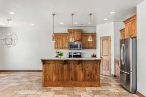 Kitchen featuring stainless steel appliances, a center island with sink, pendant lighting, and light tile patterned floors