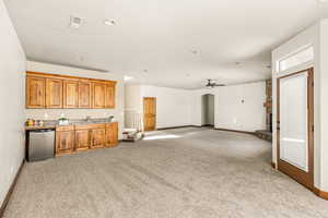 Kitchen featuring sink, ceiling fan, stainless steel dishwasher, and light colored carpet