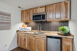 Kitchen with dark hardwood / wood-style floors, sink, stainless steel appliances, and decorative backsplash