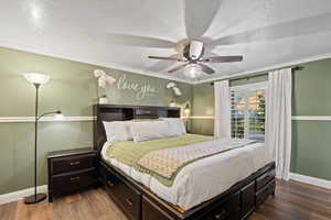 Bedroom with a textured ceiling, ceiling fan, ornamental molding, and wood-type flooring