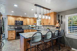 Kitchen with appliances with stainless steel finishes, decorative light fixtures, decorative backsplash, a textured ceiling, and kitchen peninsula