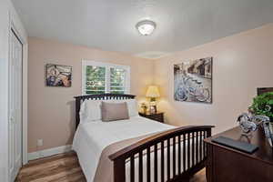 Bedroom with hardwood / wood-style floors, a closet, and a textured ceiling