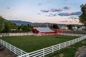 Yard at dusk featuring a rural view, a mountain view, and an outdoor structure