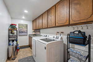 Washroom featuring light tile patterned floors, washing machine and dryer, and cabinets