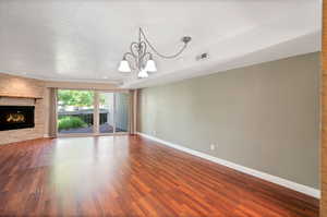 Unfurnished living room with a fireplace, a textured ceiling, and hardwood / wood-style floors