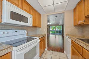 Kitchen with light wood-type flooring, tasteful backsplash, a textured ceiling, and white appliances