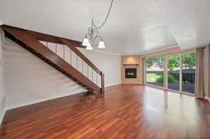 Unfurnished living room featuring hardwood / wood-style floors, ornamental molding, a textured ceiling, and a fireplace