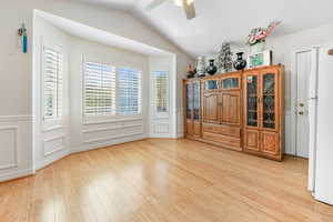 Unfurnished bedroom featuring ceiling fan, lofted ceiling, and light wood-type flooring