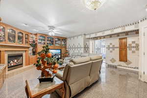 Living room with a textured ceiling, tile walls, ceiling fan, and a tile fireplace