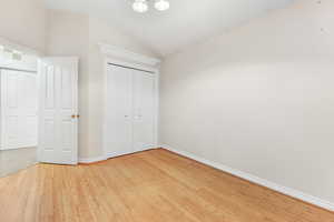 Unfurnished bedroom with lofted ceiling, hardwood / wood-style flooring, and a closet