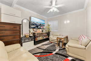 Tiled living room with ceiling fan and ornamental molding