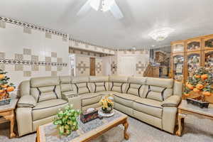 Living room with tile walls, a textured ceiling, and ceiling fan