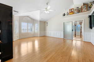 Unfurnished living room with light hardwood / wood-style floors, ceiling fan, and vaulted ceiling