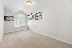 Unfurnished room with light carpet and vaulted ceiling