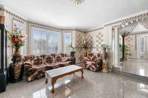 Living room featuring crown molding, decorative columns, and a textured ceiling