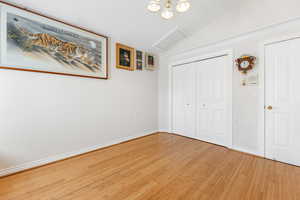 Unfurnished bedroom with vaulted ceiling and hardwood / wood-style floors