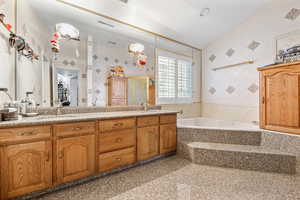 Bathroom with dual vanity, tiled tub, and tile walls