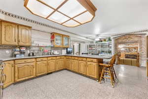 Kitchen with ceiling fan, a kitchen breakfast bar, backsplash, sink, and kitchen peninsula