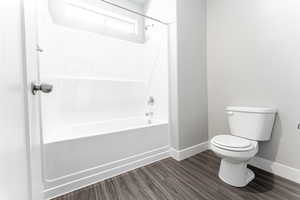 Bathroom featuring toilet,  shower combination, and hardwood / wood-style floors